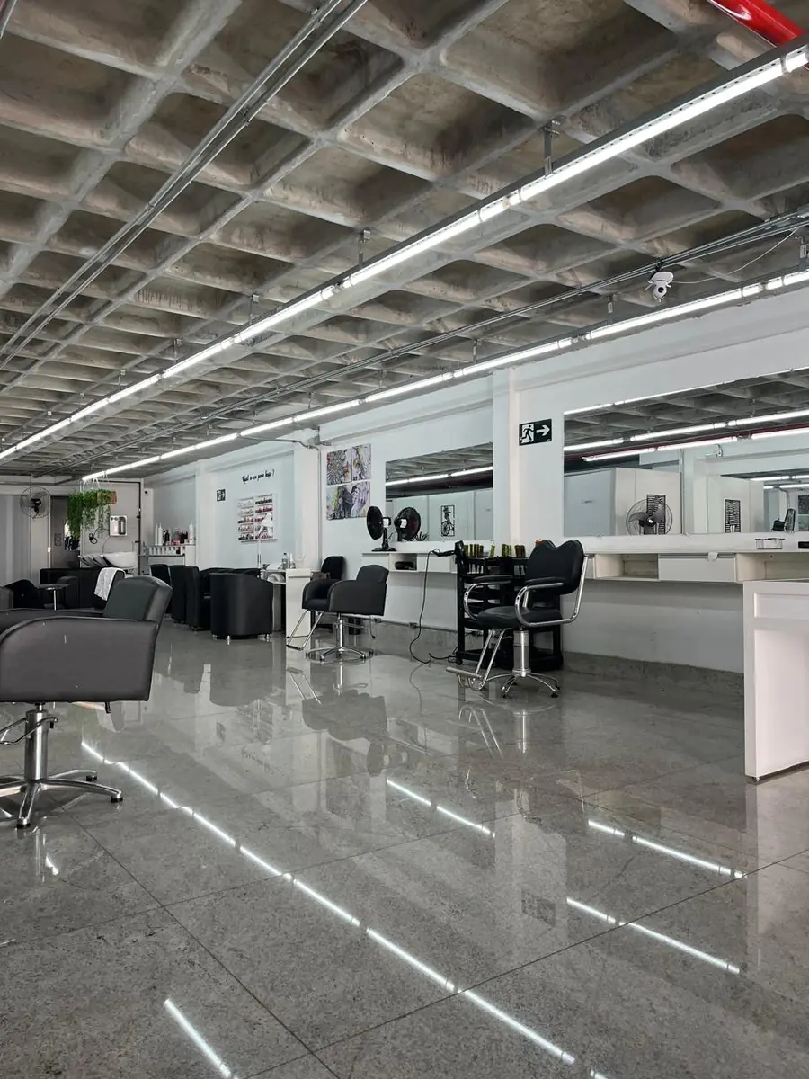Salão do estúdio visto de ponta a ponta, com estações de cabelo e piso de granito